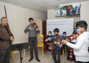 Elleri bir yandan keman bir yandan kalem tutuyor