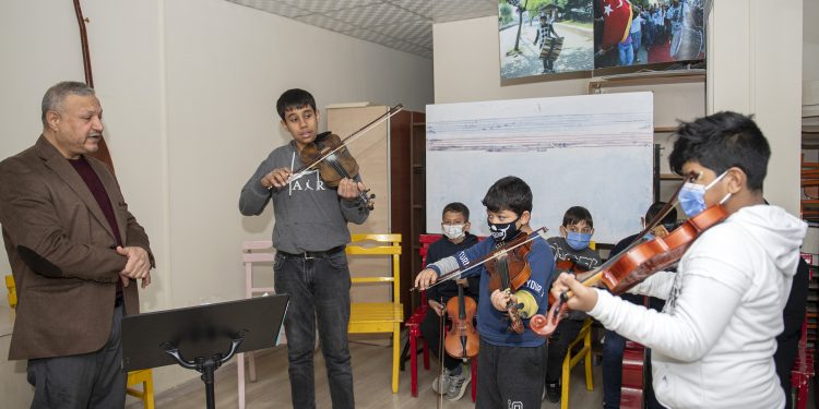 Elleri bir yandan keman bir yandan kalem tutuyor